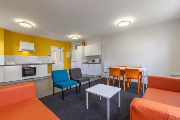 Shared kitchen with oven, sinks, cupboards, hobs, microwave, fridge, dinning table and sofa area