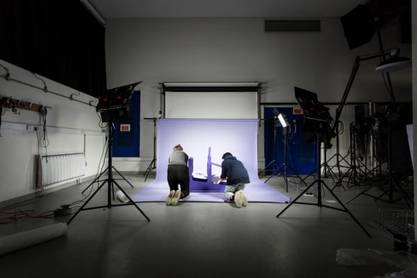 Two people in the London College of Communication photographic studio bent down on the floor