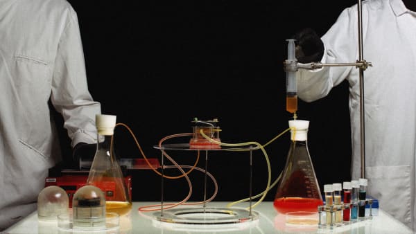 Two people wearing lab coats holding lab equipment