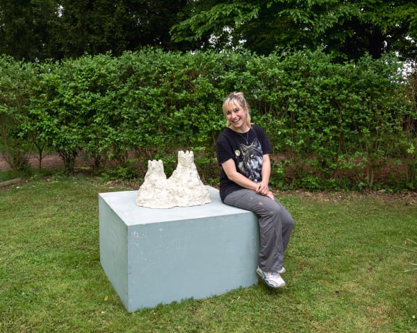 student standing next to their sculpture
