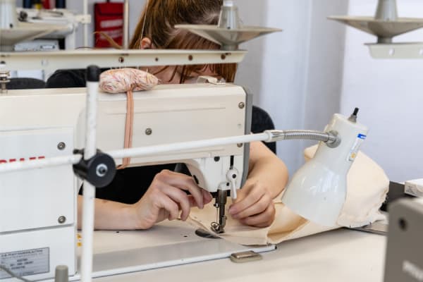 Close-up of student using sewing machine inside workshop. Photography Ana Blumenkron.