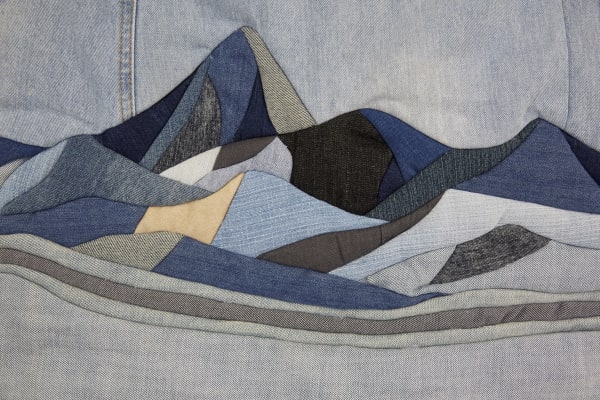textile design of a mountain scene in different colours of denim fabric. 