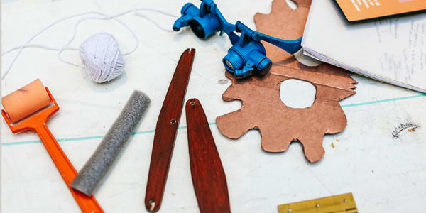 Table top with various tools laid out including an ink roller, string, eye glasses 