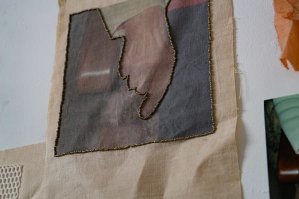 A wall hanging with an embroidered hand pointing down