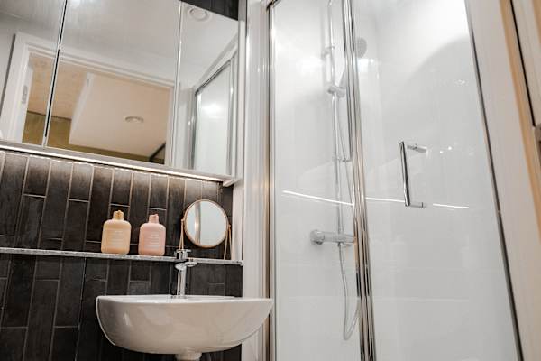 Grey tiled bathroom with shower, sink and toilet.