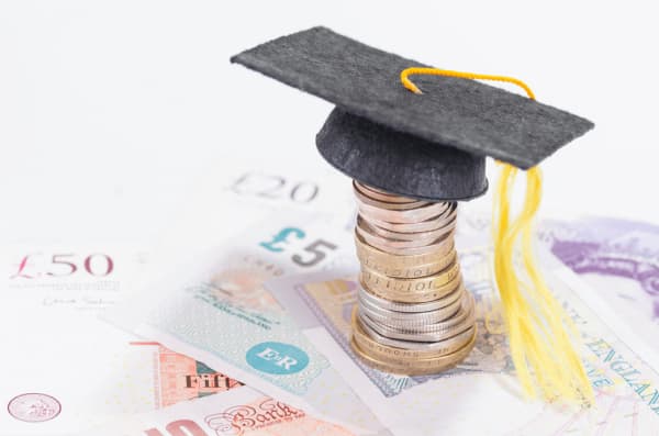 Photograph of a stack of coins with a miniature graduation cap on top 