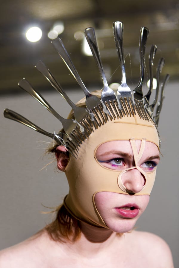 Portrait of a face wearing a mask of metal spoons
