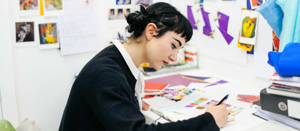 Student at a desk illustrating on a sketchbook