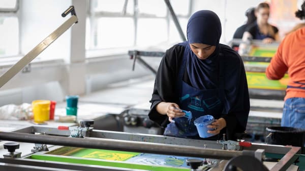 A student preparing paint for a screen print.
