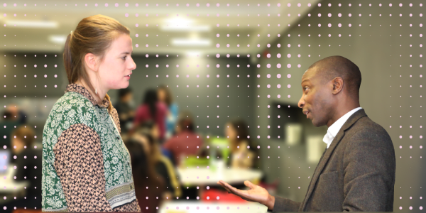 A photograph of two people in conversation with each other, overlaid with a pattern of pink dots.