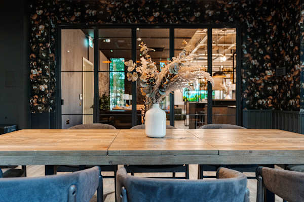 A large wooden dining table with a vase of flowers on it.