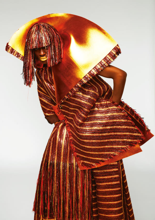 Woman wearing outfit woven in oranges and bronzes