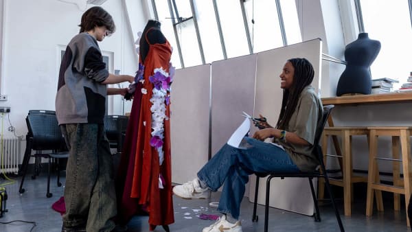 Two students working on a garment pinned to a dressmaker dummy