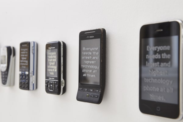 Installation of old mobile phones attached to a white wall