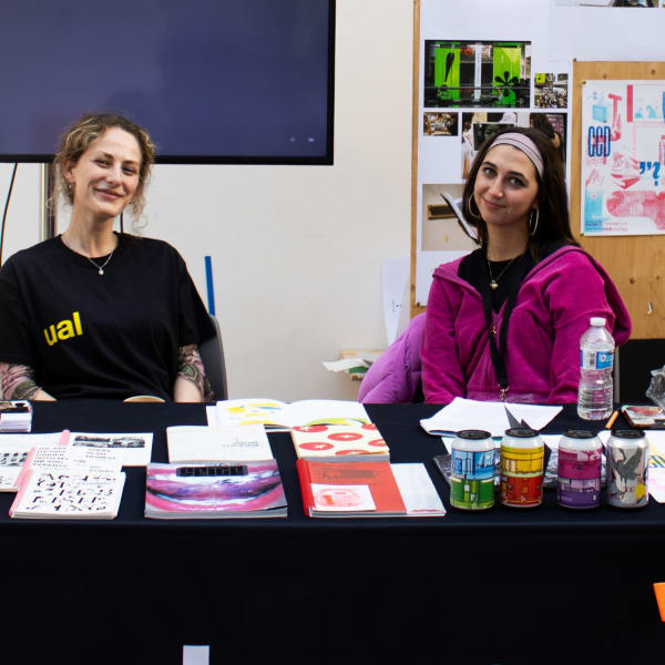 Students at a desk smiling 
