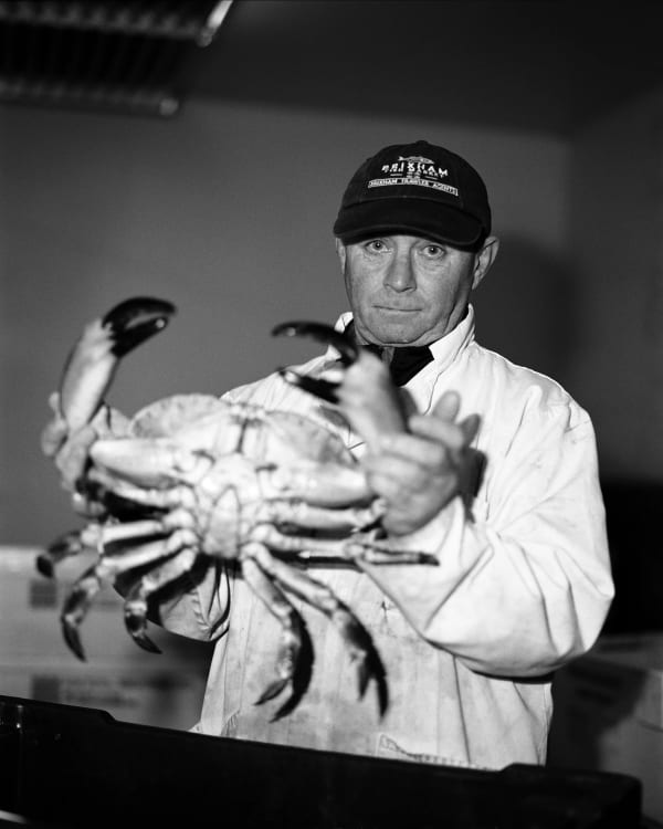 A man wearing a baseball cap holding a crab