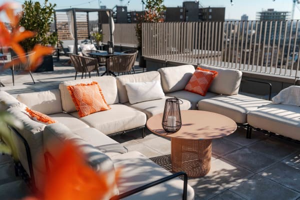 Low outdoor sofa seating on a roof terrace beside a cityscape