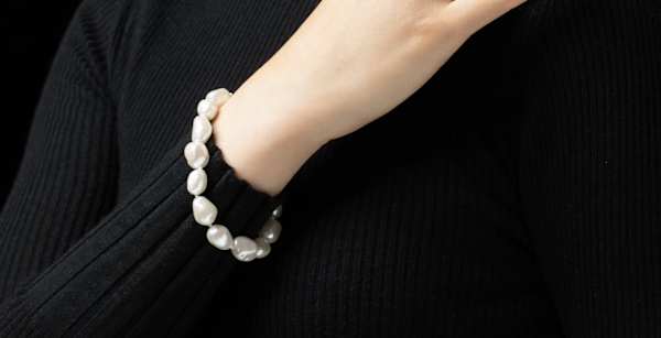 A pearl bracelet worn by a female wearing black jumper
