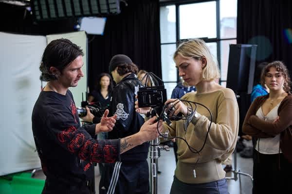 Students working with professional film and lighting equipment during a practical session in a studio at London College of Fashion.