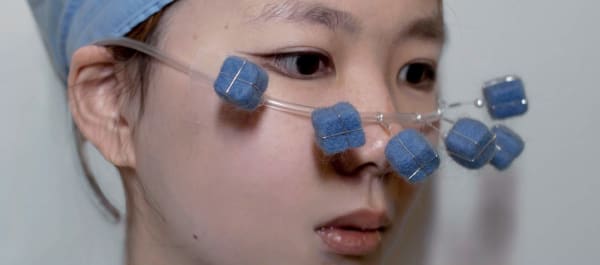 Close-up of face covering made of plastic tubing and blue felt cubes
