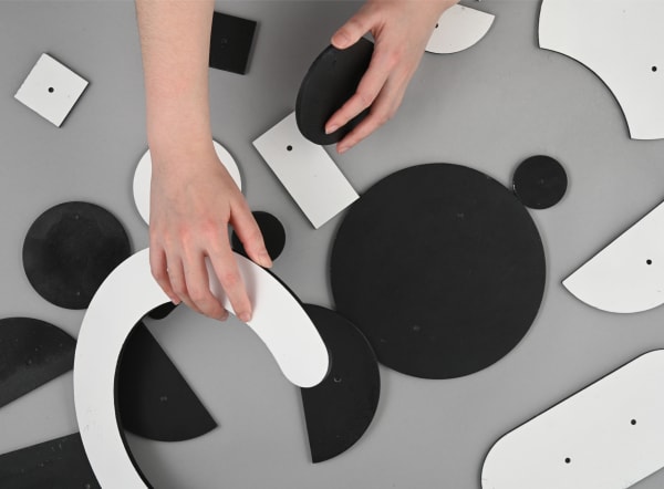 Hand moving various black and white shapes across a table