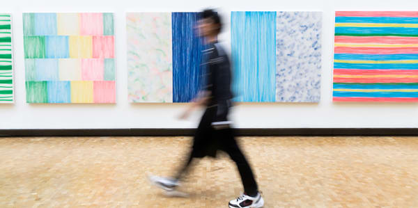 Blurred image of person walking in front of an artwork