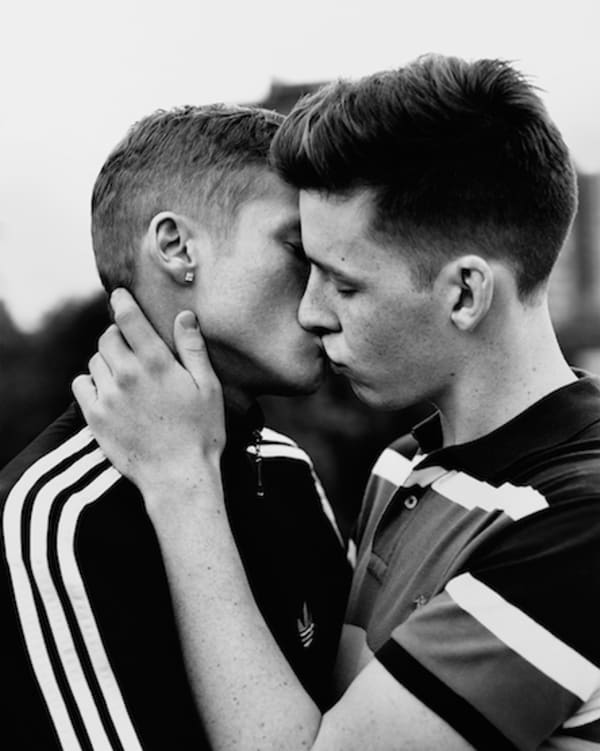 black and white photo of a couple kissing, both in striped sports uniform.