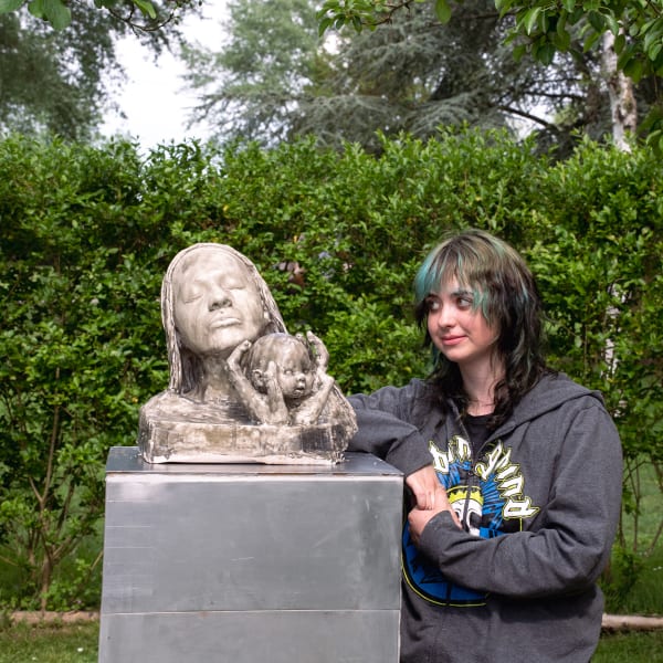 student standing next to their sculpture