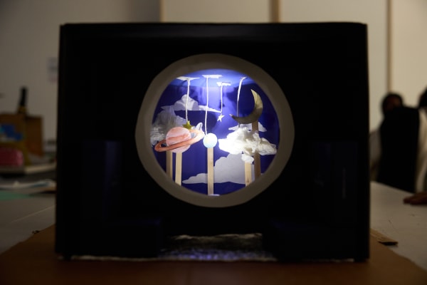 A diorama of a night sky with a moon, clouds and planets