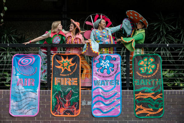 Students in costumes on a balcony with colourful banners 