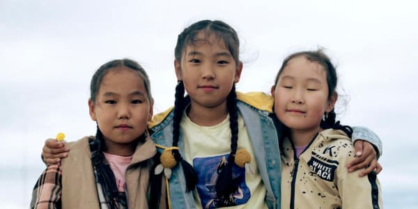 Three children standing together with their hands around each other