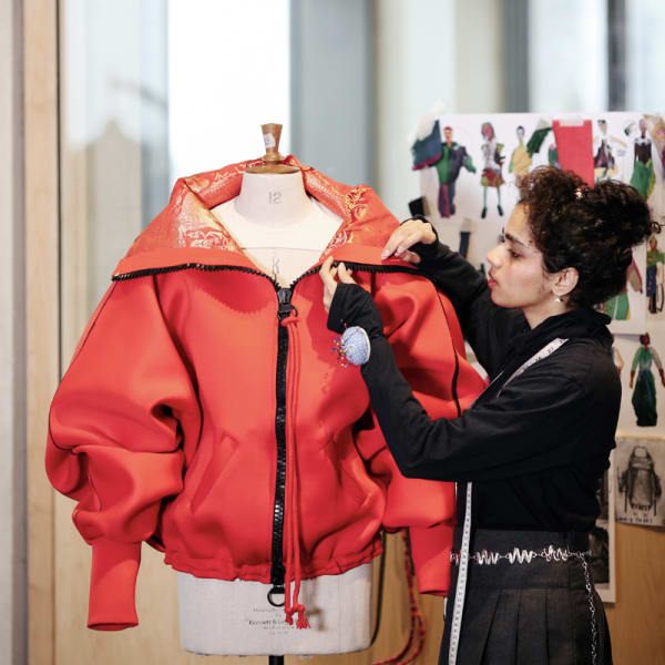Student adjusting jacket on a mannequin