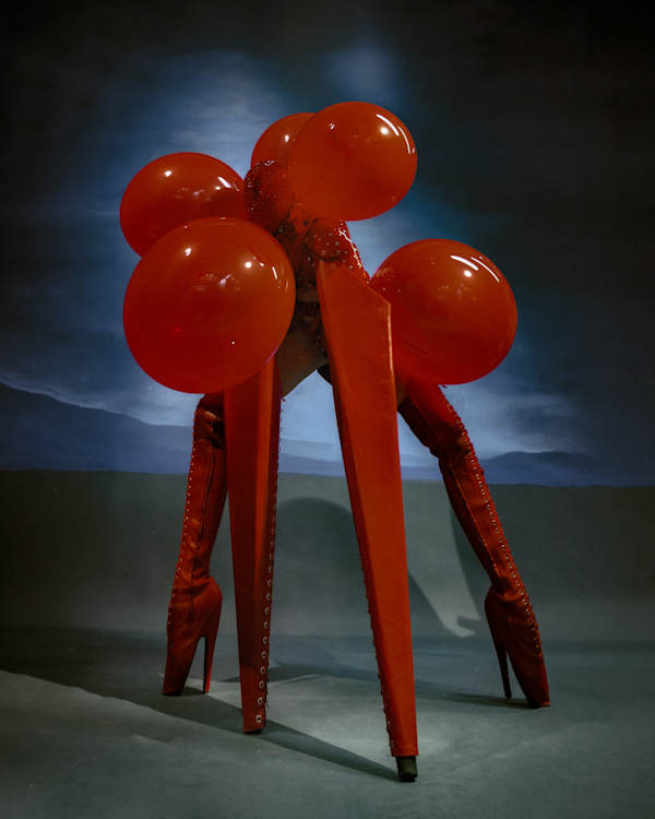 Sculptural red costume with balloons and towering platform boots.