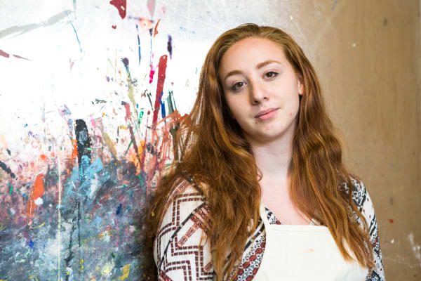 Headshot of Emma in the Summer Study Abroad Textile Design Workshop, in front of a colourful wall