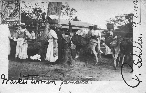 A black and white image of market women in Jamaica wearing aprons and standing with cattle