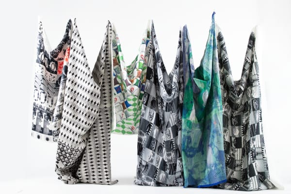 Six patterned fabrics hung from a white wall