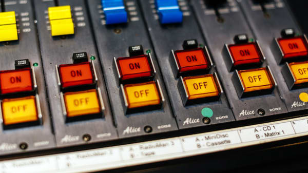red 'on' and yellow 'off' buttons on a sound mixing desk