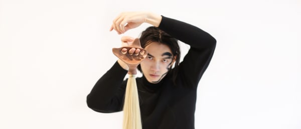 Male model holding a headpiece made of Chinese calligraphy brush material.