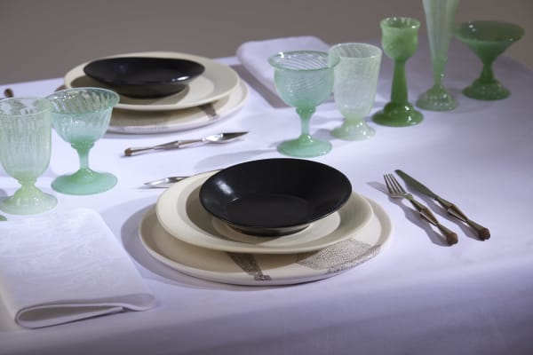 A table with a white table cloth set with plates, cutlery and glassware