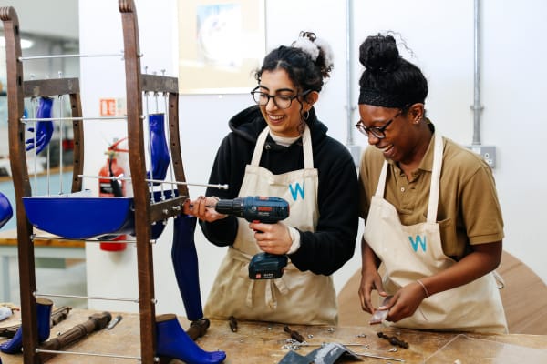 Two students are working together to build a wooden chair.