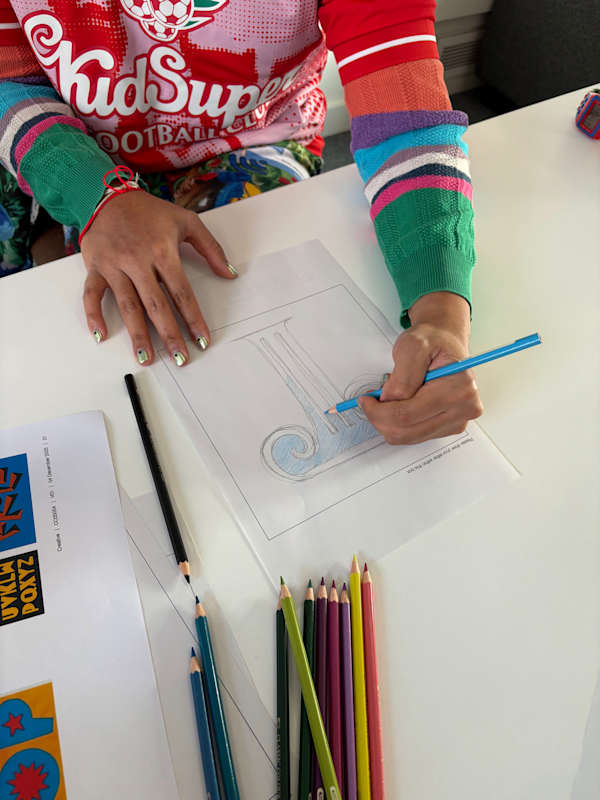 Participant sketching the letter “T” during a typography workshop, surrounded by pencils and sketch papers.