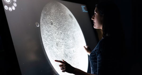Photo of a person looking at a screen showing an image of the moon.