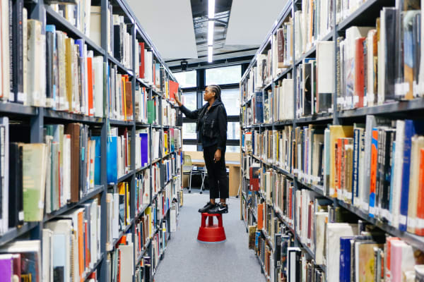 A student using a stepping stool in the LCC library