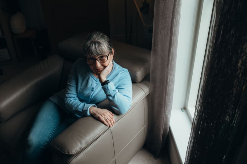 A women sits on an armchair with her head in one hand. 