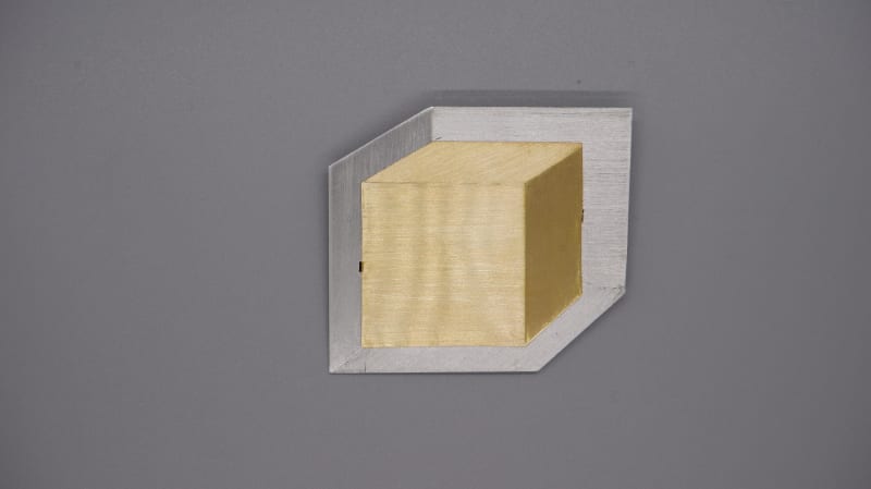 brass cube in a silver square space