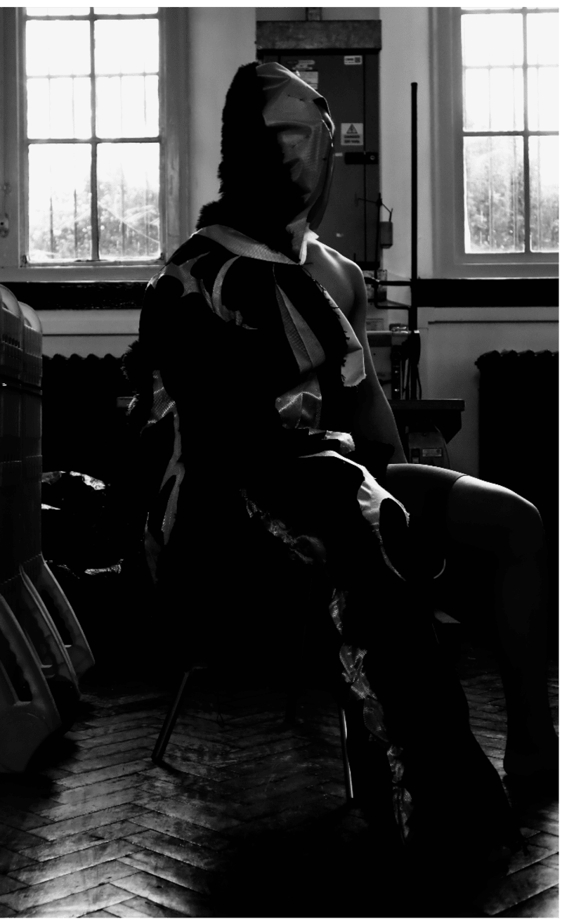 man sitting wearing abuser garment and standing leaning back wearing victim garment