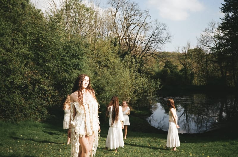 Group of girls together in a field next to a lake.