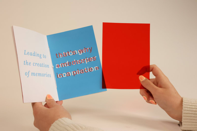 Hands holding a red coloured film about to lay over the publicaciones page.