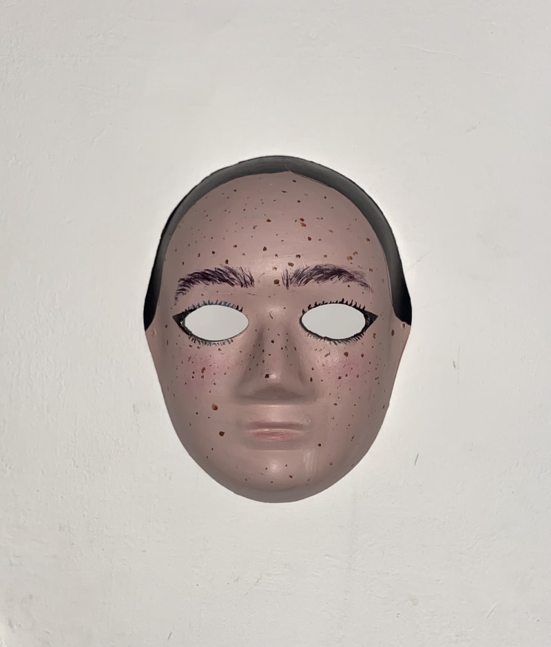 A mask on a wall. Representing a face.