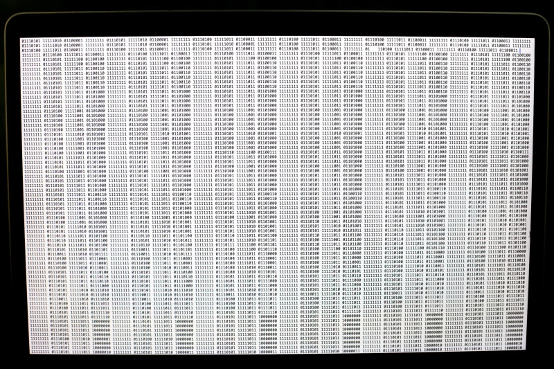 Detail showing laptop display: binary data generated from the image